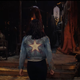 a girl standing in a jacket with a star on its back.